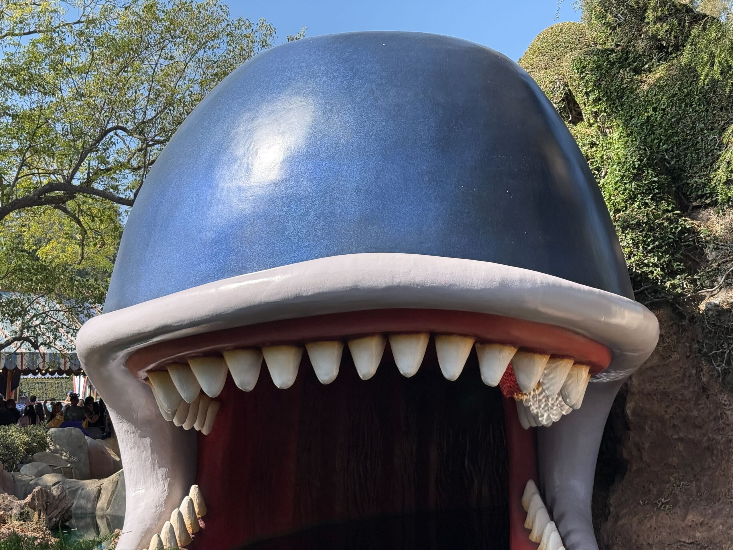A large whale sculpture with its mouth open wide and big teeth, resembling Disneyland's Storybook Land Canal Boats entrance.