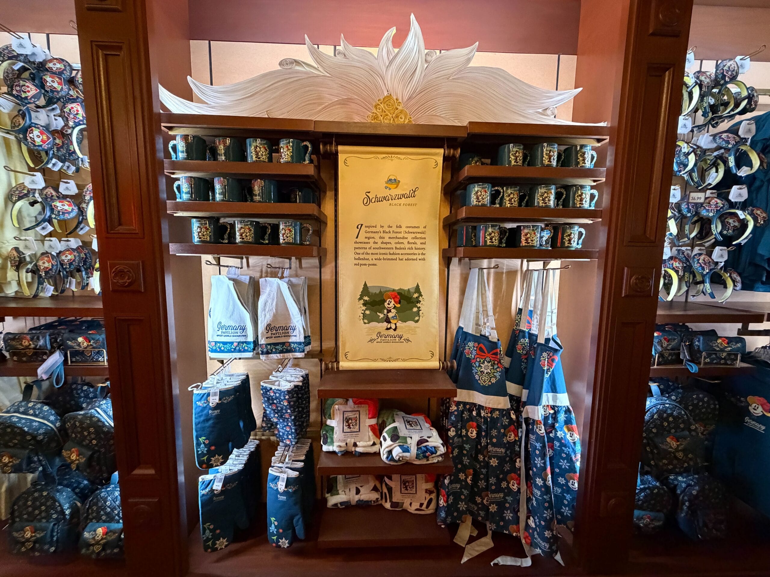 Snow White-themed merch display at a Disney park, with mugs, bags, and a Black Forest story scroll—no castle visible to compare.