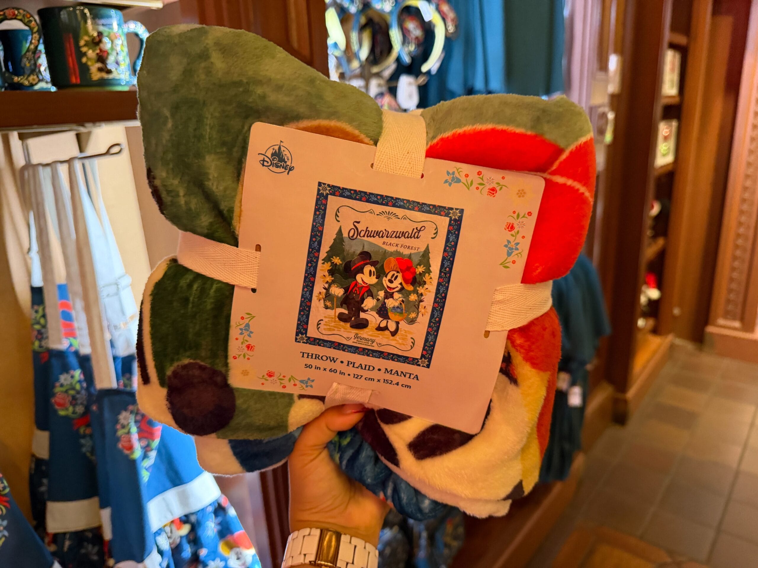 A hand holds a Mickey and Minnie blanket in a Disney store in Germany; unlike park shops, no castle merchandise is displayed here.