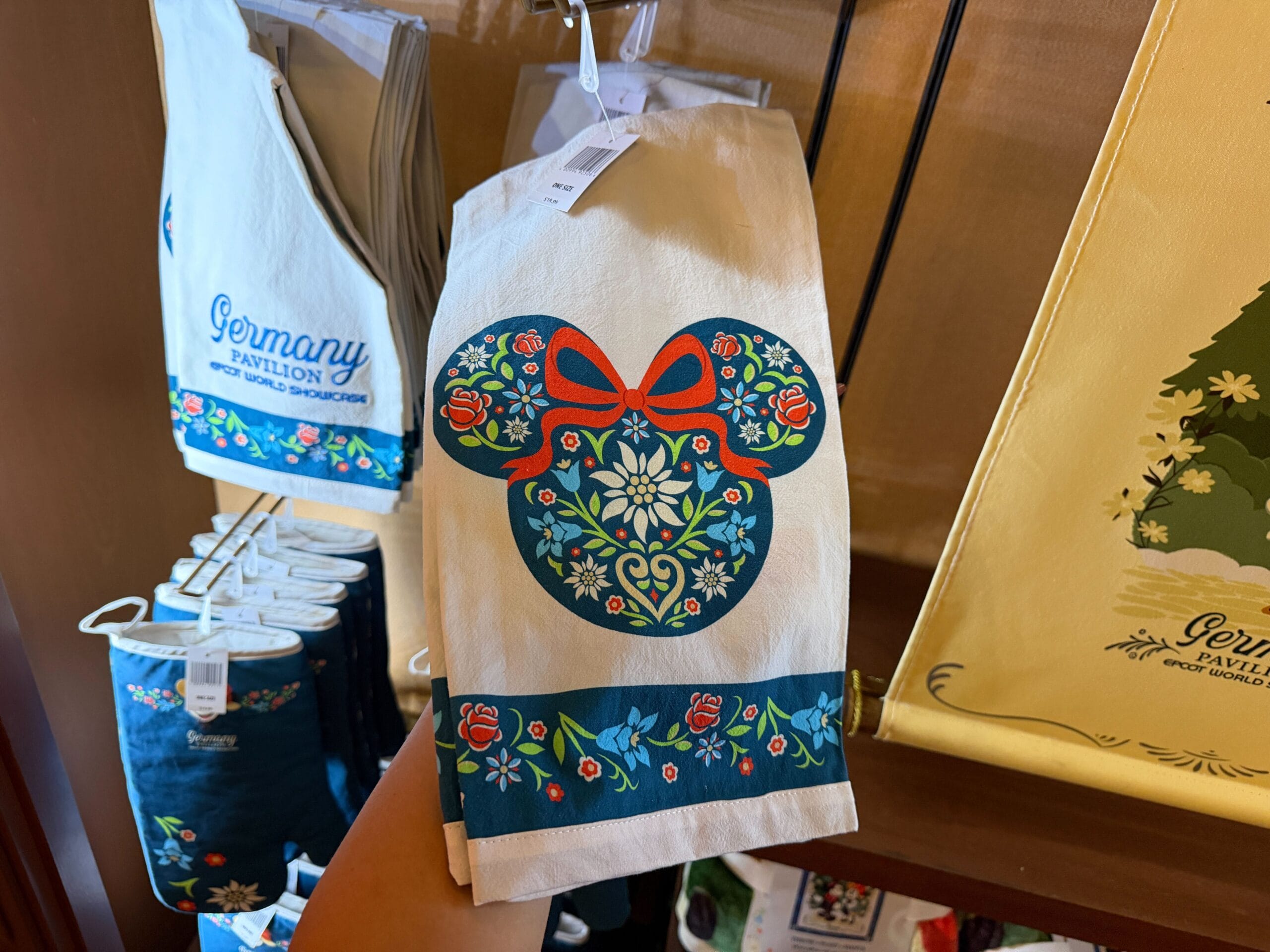 A tea towel with a floral Mickey Mouse head and bow, echoing German Black Forest style seen in Epcot’s Germany Pavilion merch.