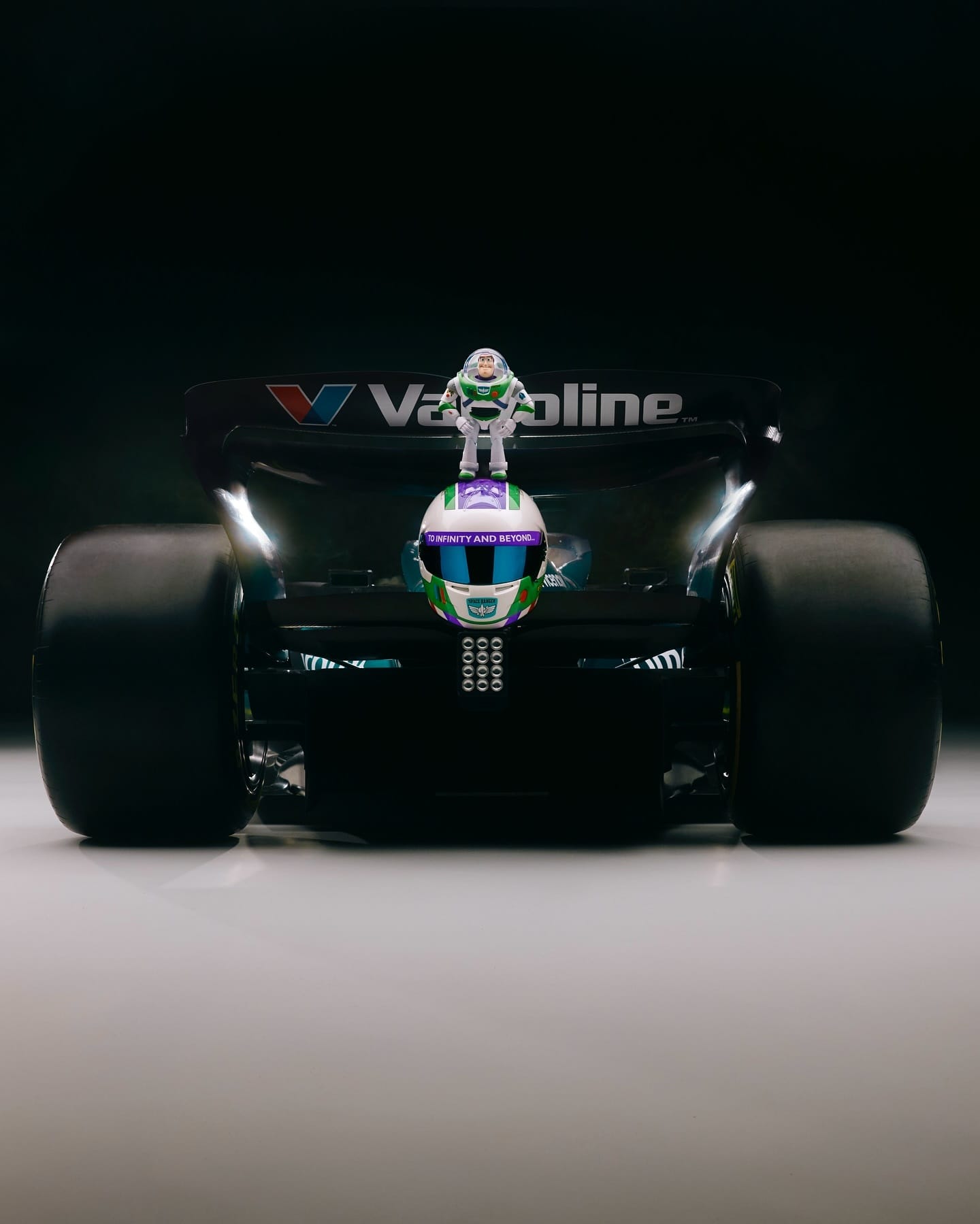 A Buzz Lightyear toy perches on the rear wing of a Valvoline Formula 1 car, blending Disney magic with racing excitement.
