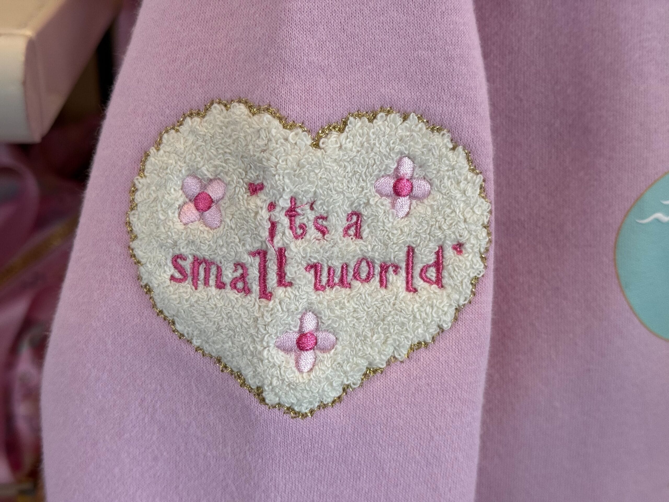 the right sleeve close up of the it's a small world pullover sweatshirt by stony clover lane