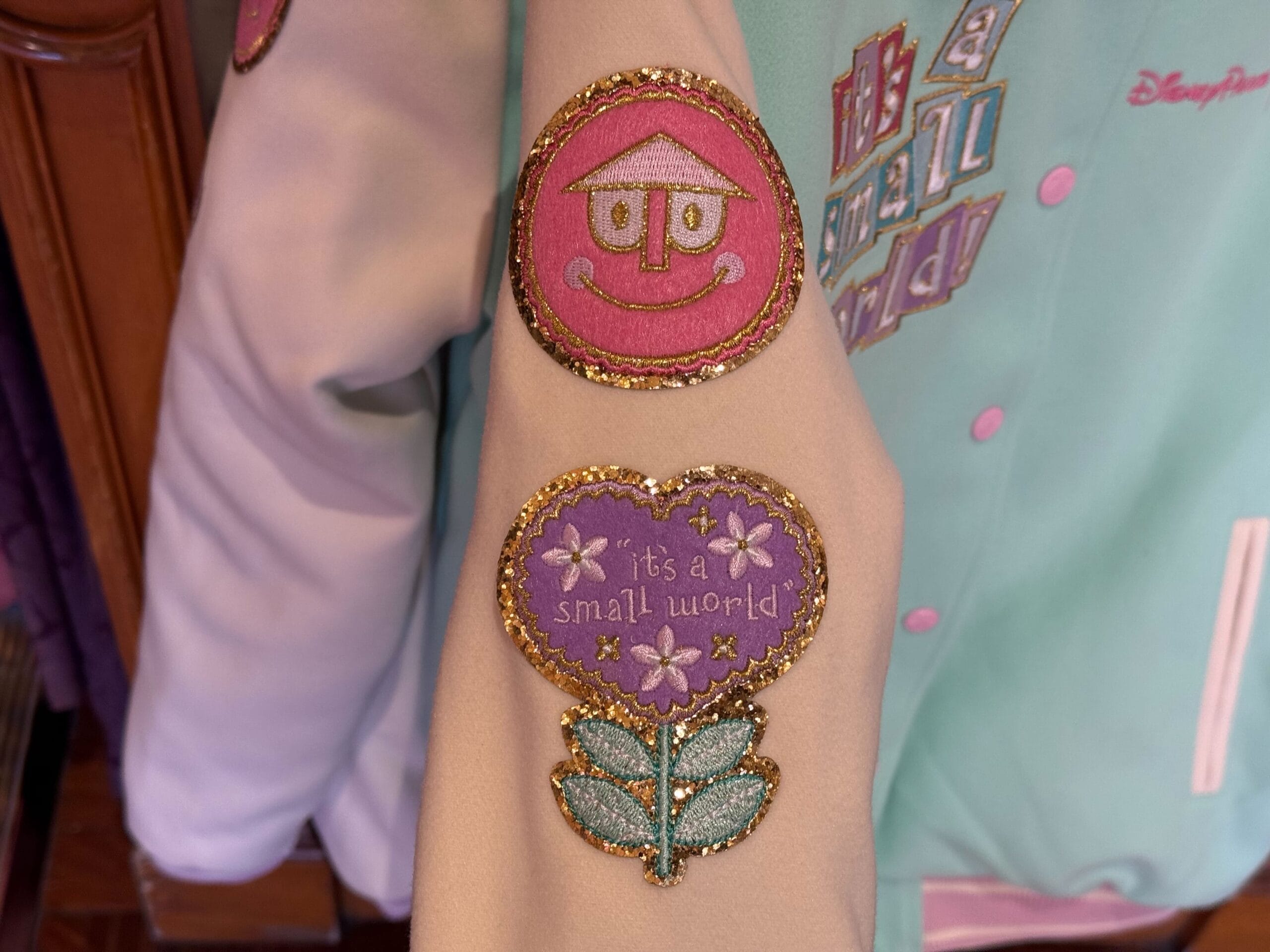 The Letterman-style jacket has it's a small world patches on the sleeve.