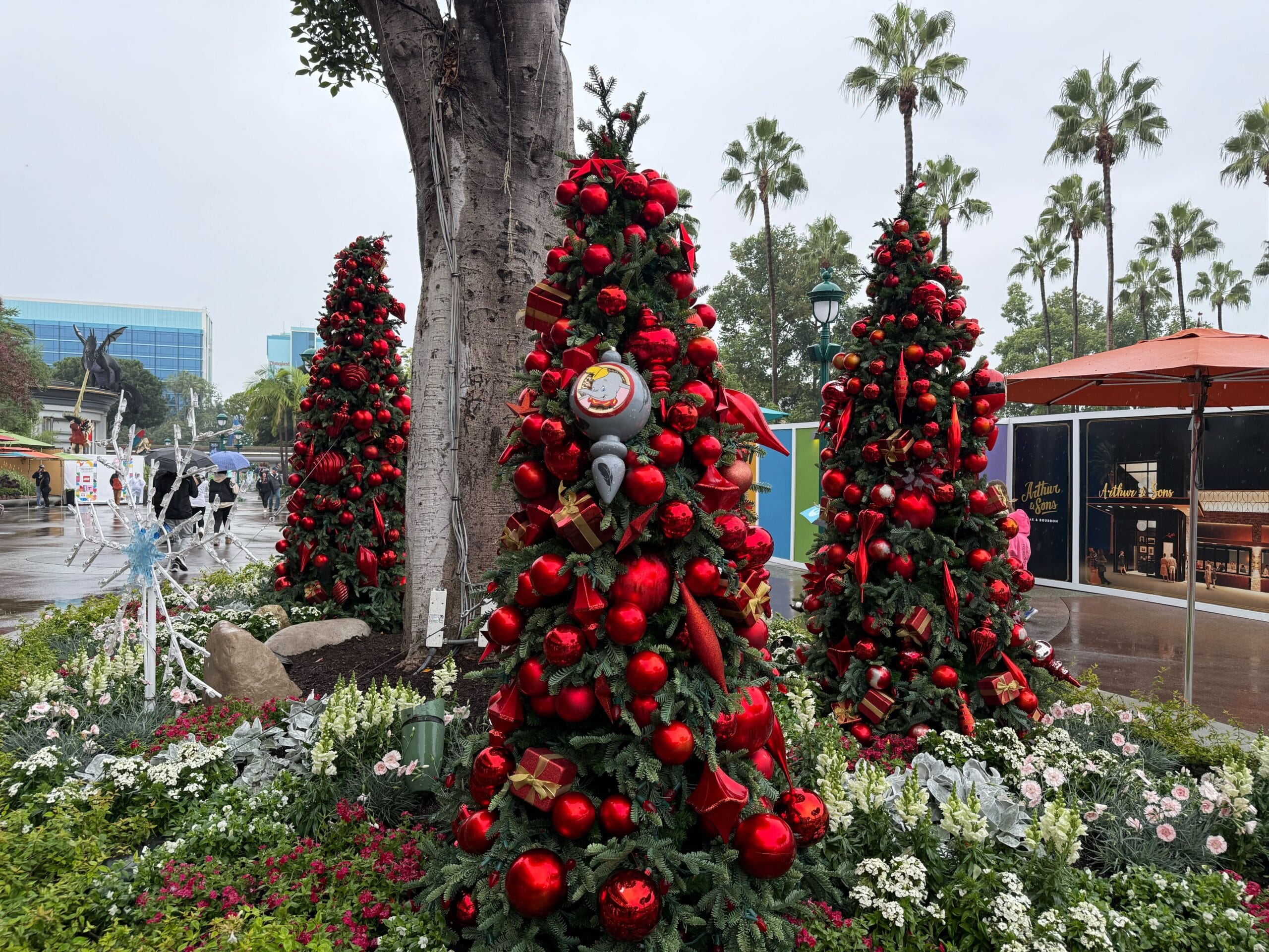 Outside Jazz Kitchen Coastal Grill & Patio, a pair of trees is covered with red ornaments in various sizes. In the flowerbed with these trees are giant light-up snowflakes.