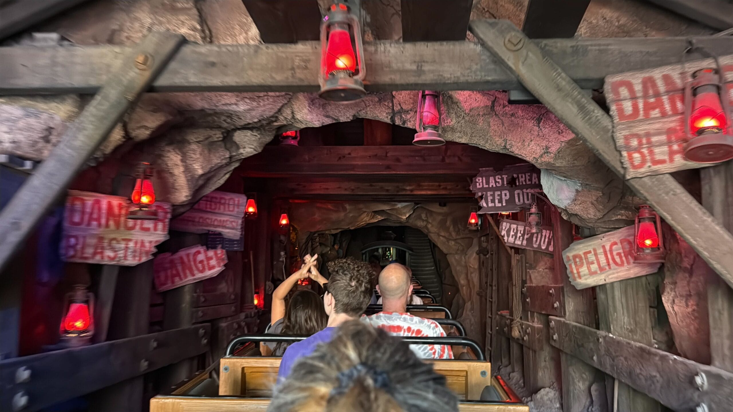 Guests enjoy Big Thunder Mountain Railroad at Disneyland, zipping through a lit rocky tunnel—not Magic Kingdom’s Florida version.