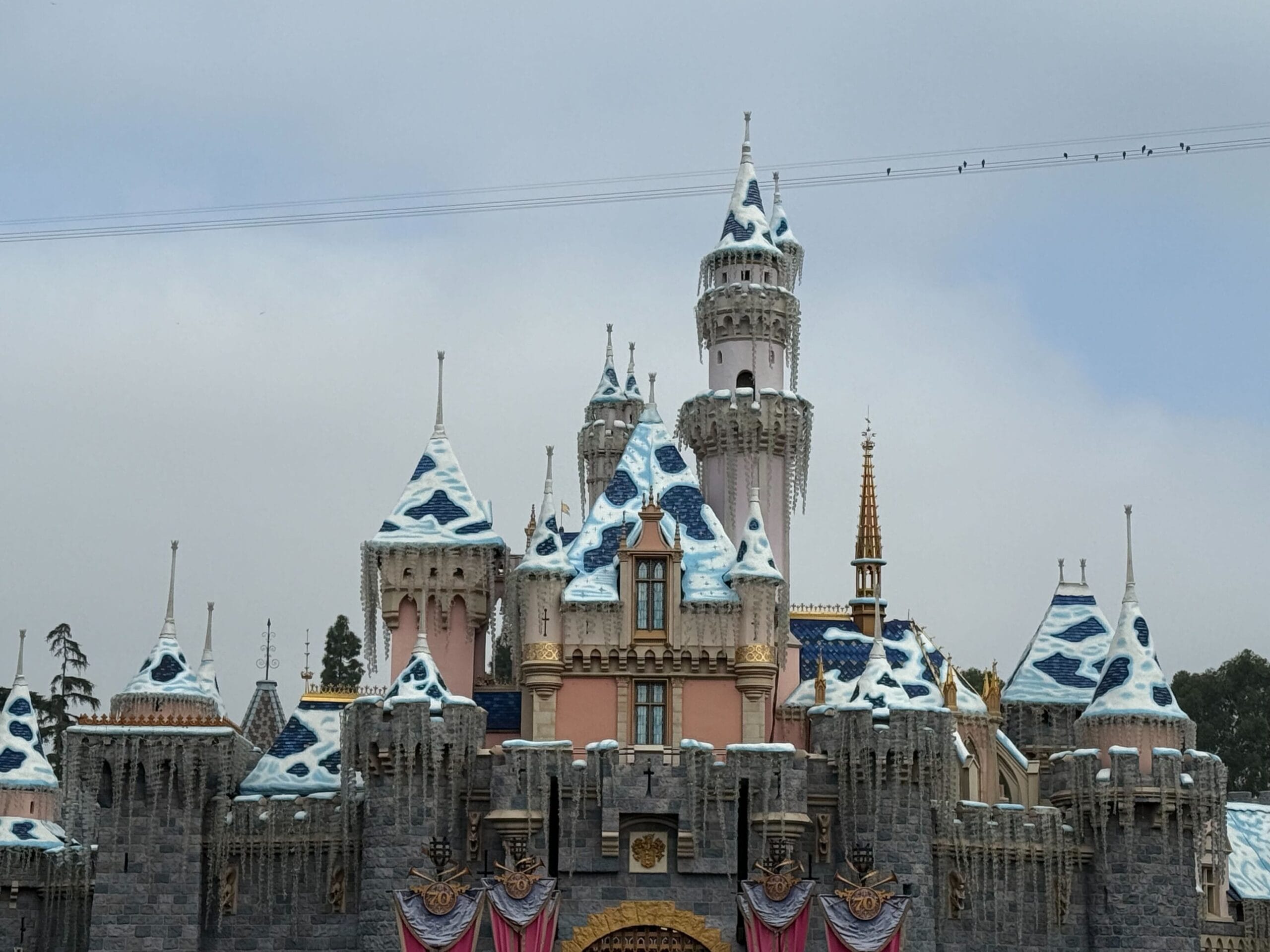 At Disneyland, snow is now fully covering Sleeping Beauty Castle completely for the 2025 holiday season.