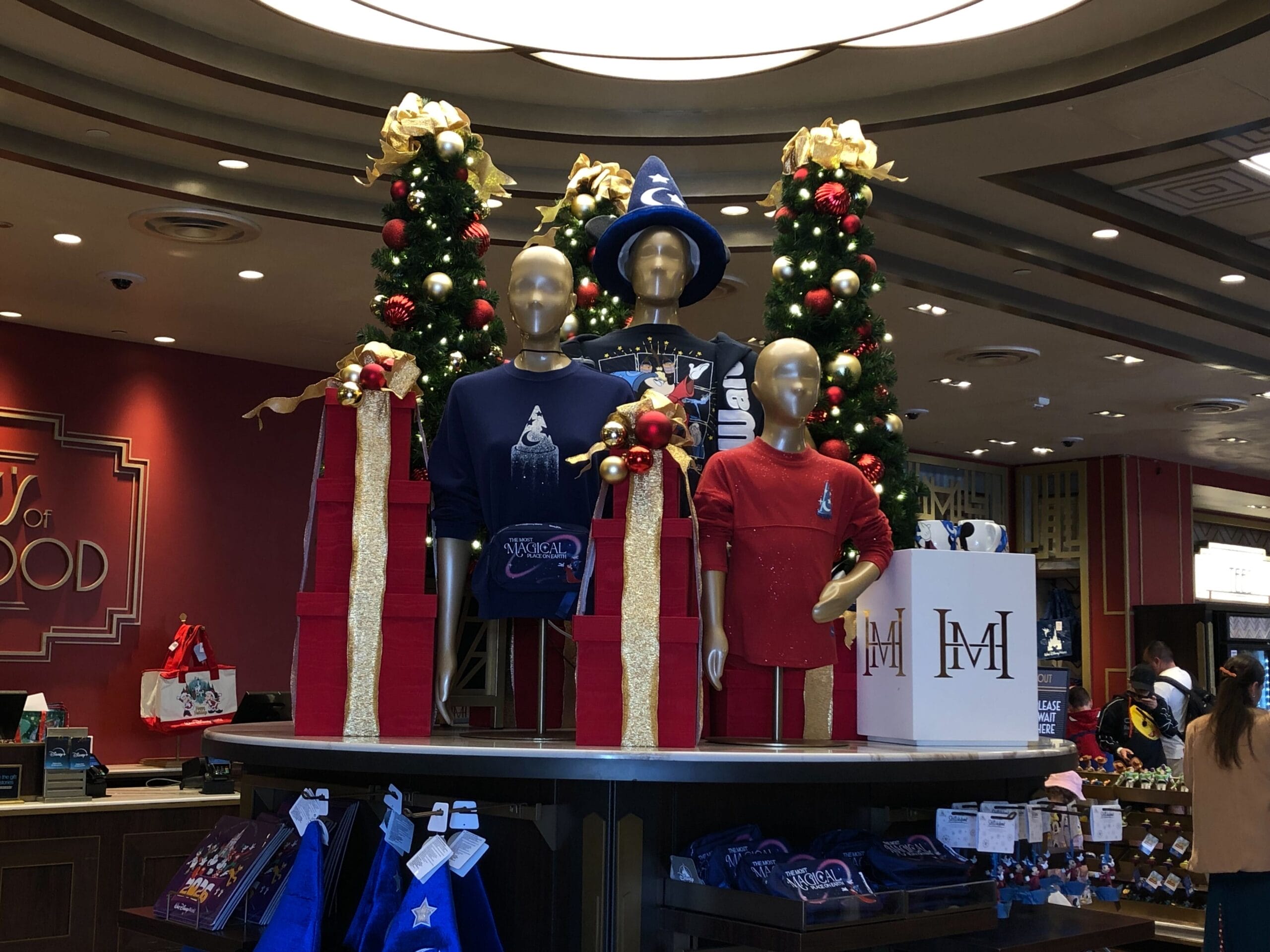 Holiday display on Sunset Boulevard: three mannequins in Disney shirts amid festive decor and gifts, echoing park magic.