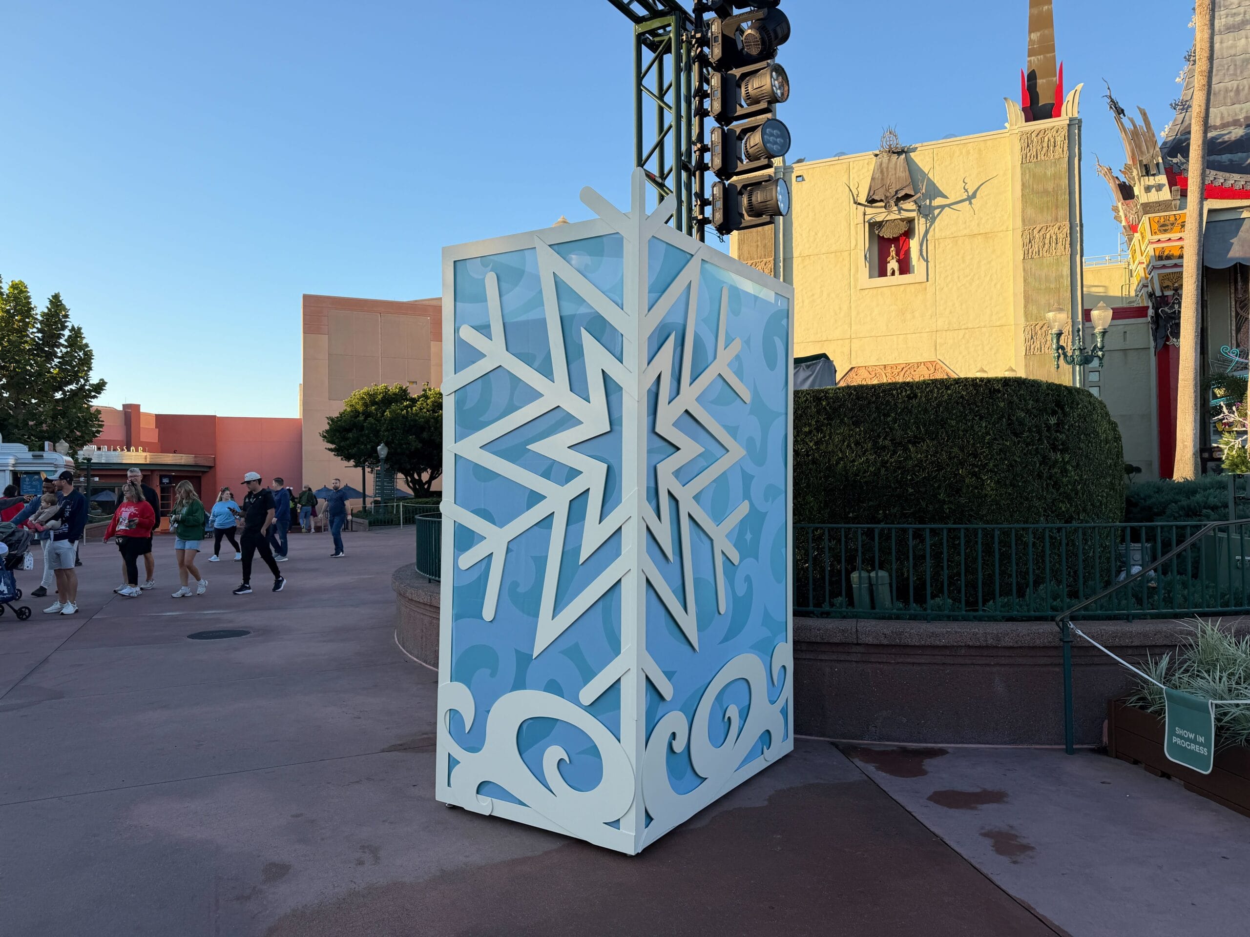 A large blue and white box with a snowflake pattern sits in an outdoor plaza at a Disney park