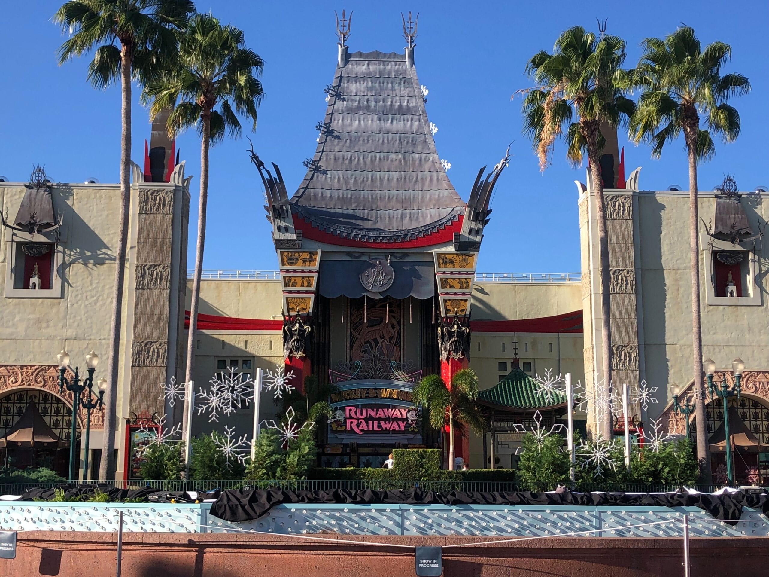 Chinese Theatre at Disney’s Hollywood Studios with Runaway Railway sign, palm trees, and blue sky