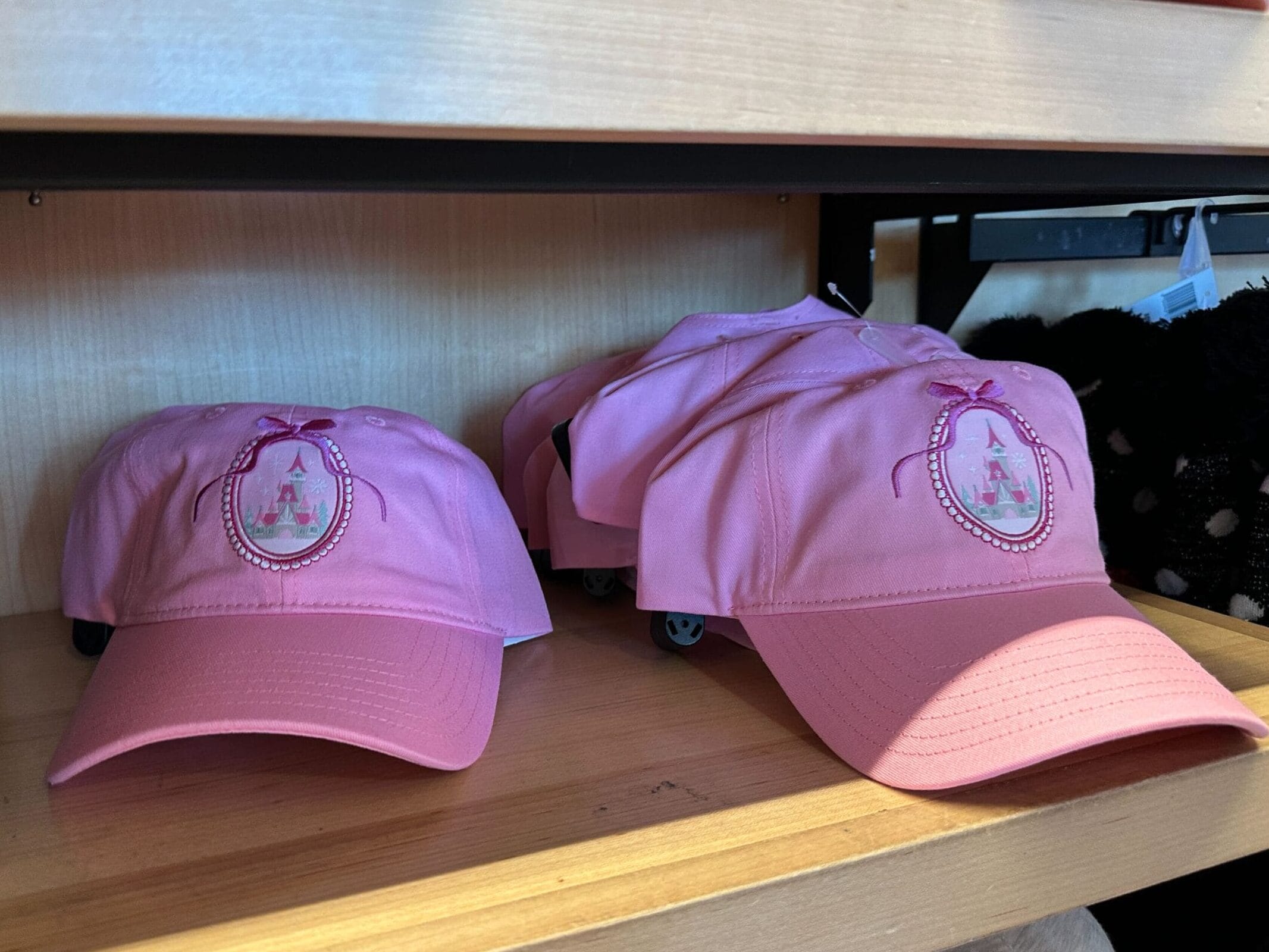 The pink baseball cap has an image of the castle inside an oval border.