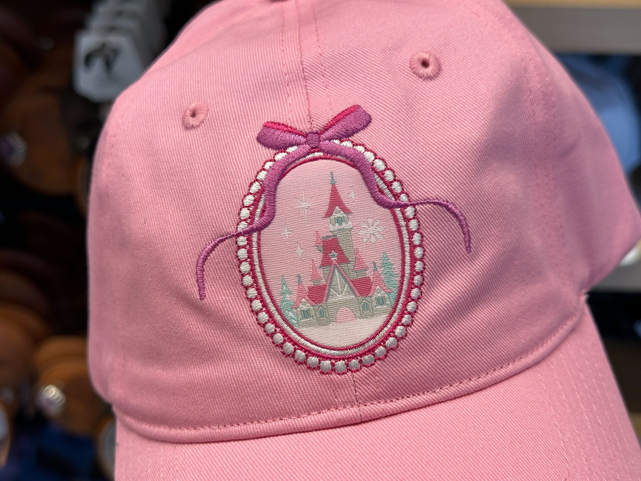 The pink baseball cap has an image of the castle inside an oval border.