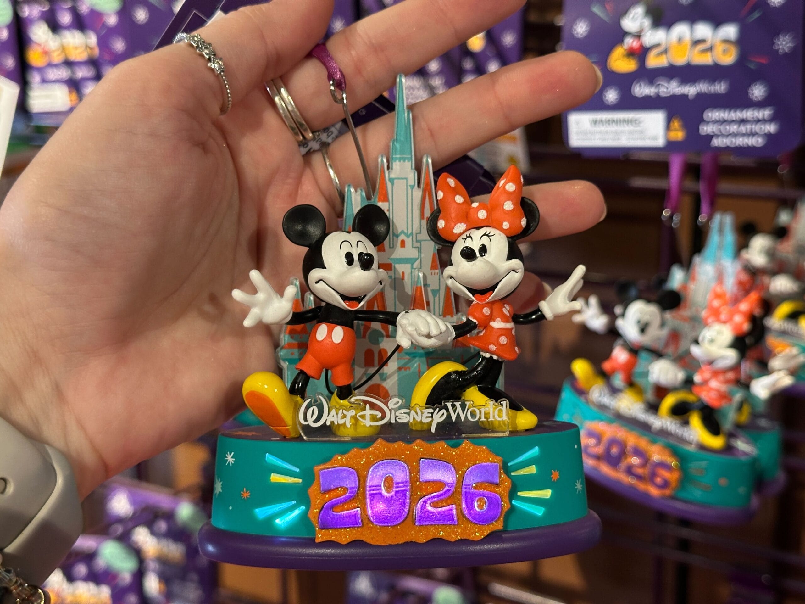 The year and bursts also light up on the base of this ornament. Mickey and Minnie figures stand in front of a flat of the castle.