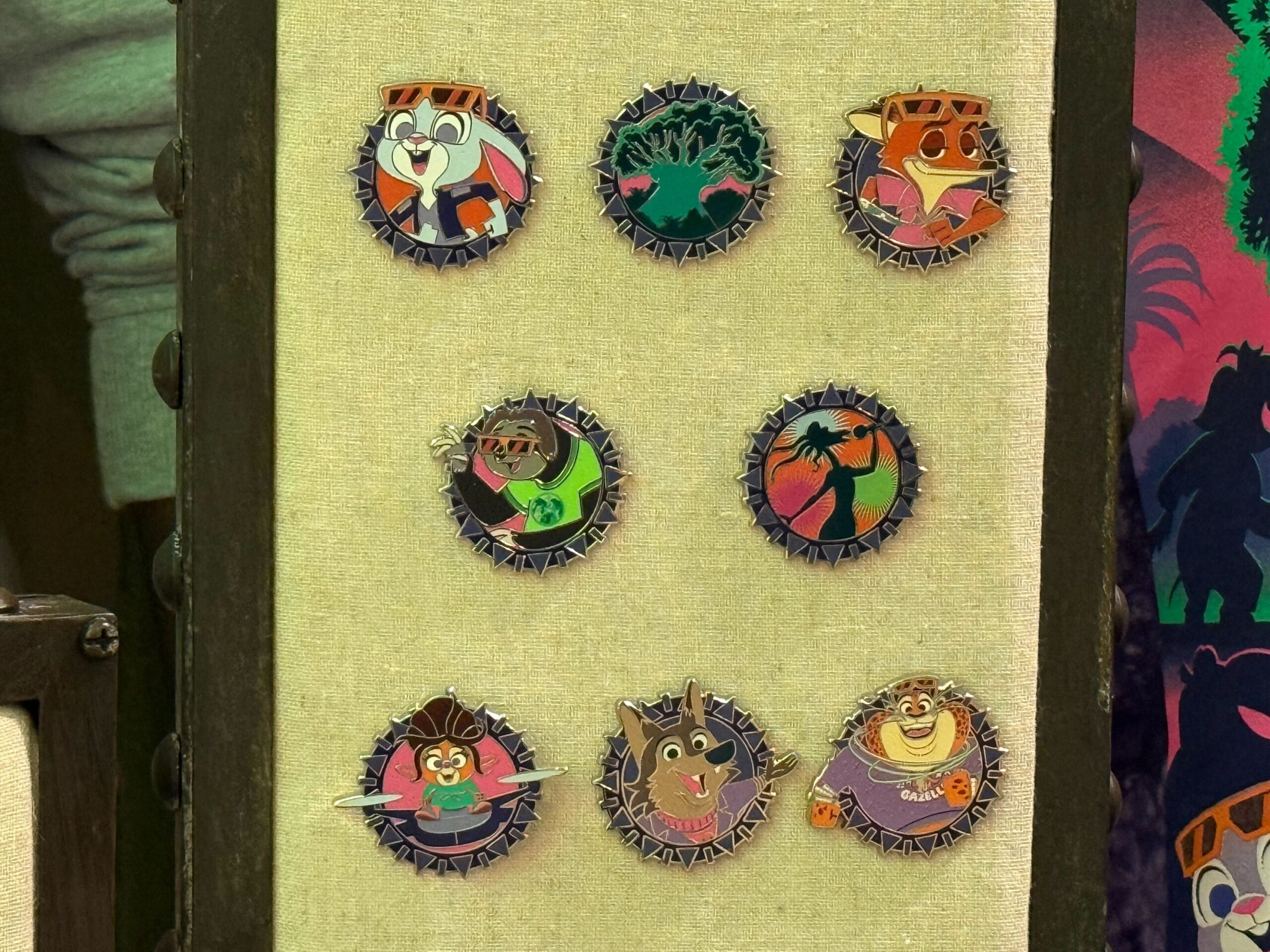 Eight colorful Disney animal character pins are arranged in two columns on a beige board, like a pin trading display at the parks.