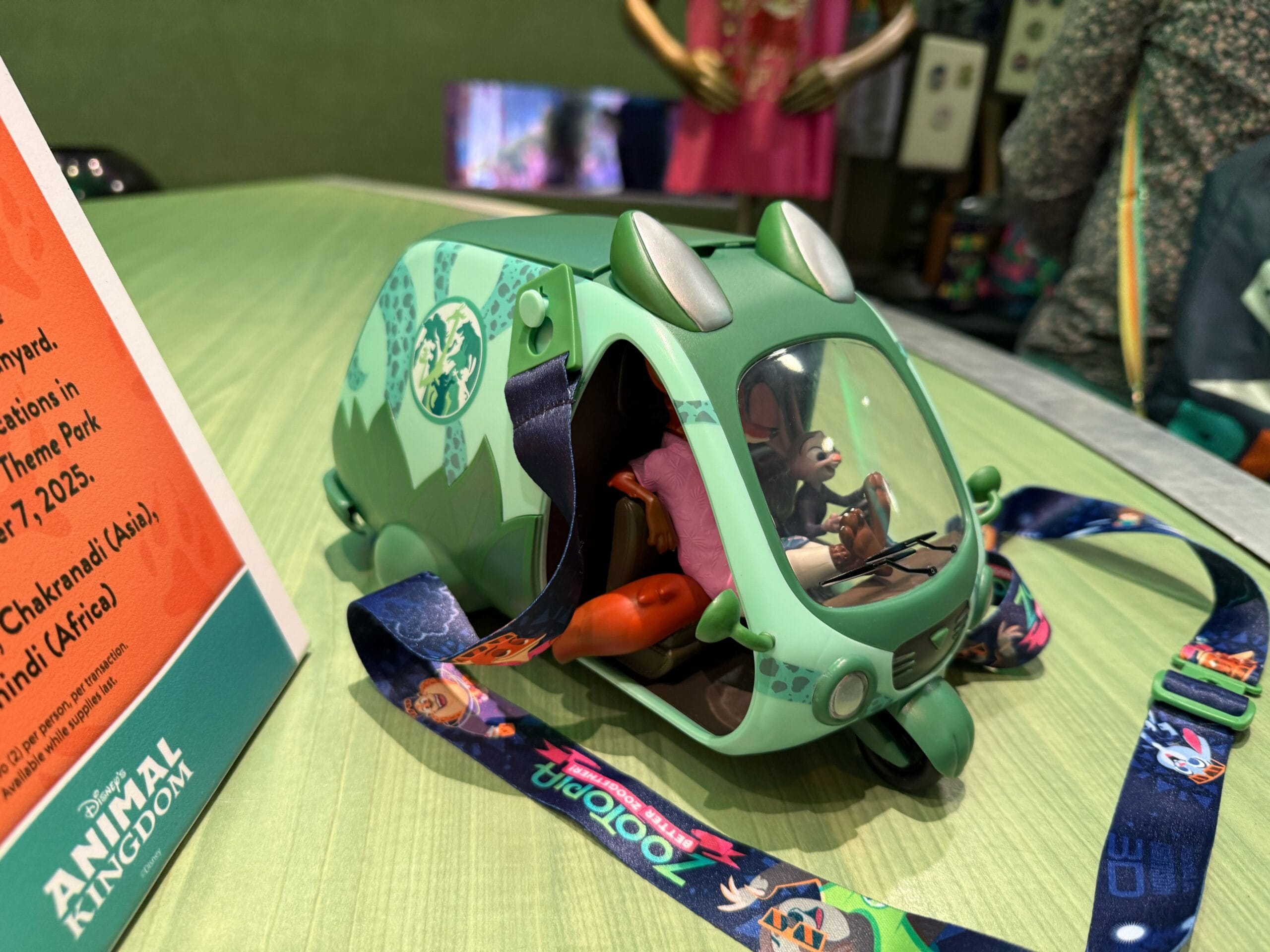 Green Zootopia popcorn bucket with Judy Hopps inside, displayed by park merchandise and signage