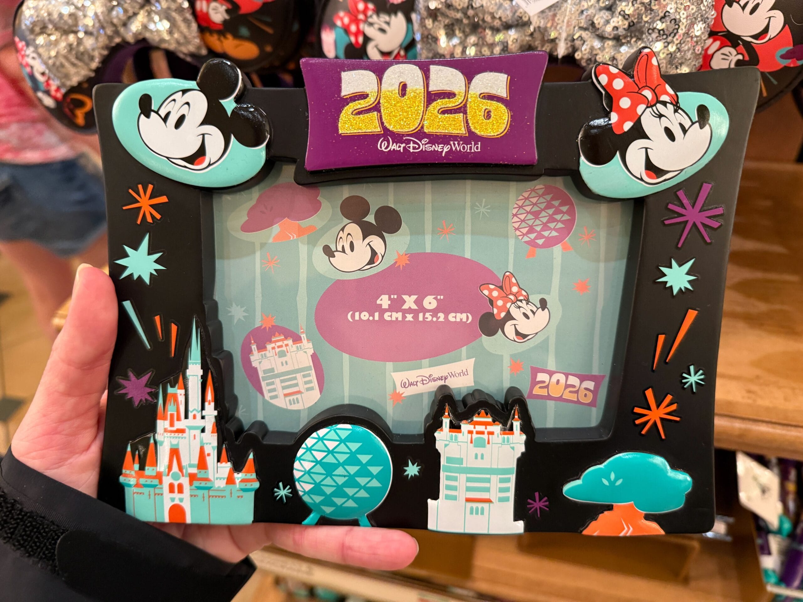 The photo frame is black with the four park icons along the bottom. Mickey, "2026", and Minnie are at the top. It holds a 4" x 6" photo.