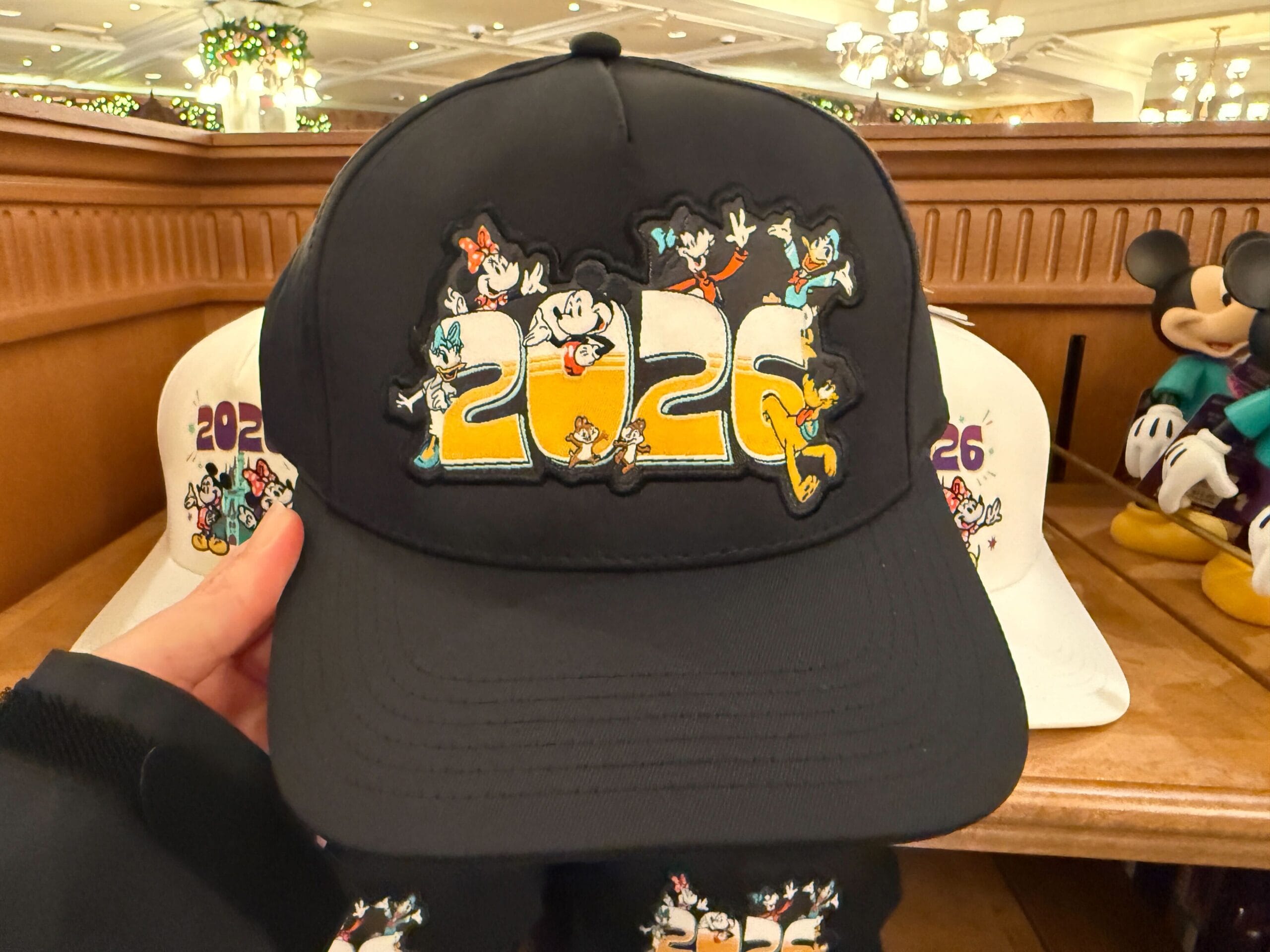 The black cap features "2026" in a yellow ombré with Mickey and Friends around it.
