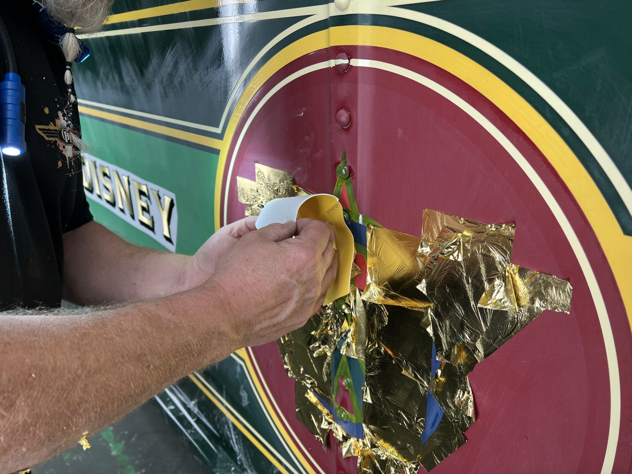 Cast Member hand-paints detailing and gold leafing on the steam train