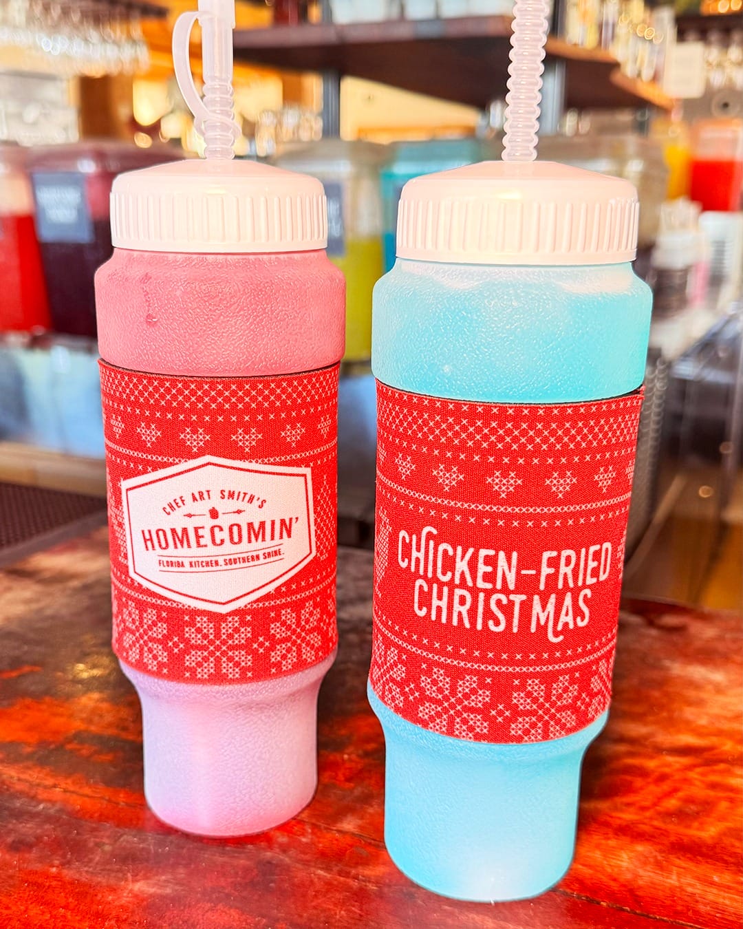 The 24 oz squeeze bottle has a red wrap around the center featuring a fair isle design. It has the Homecomin' logo on one side and "Chicken-Fried Christmas" on the reverse.